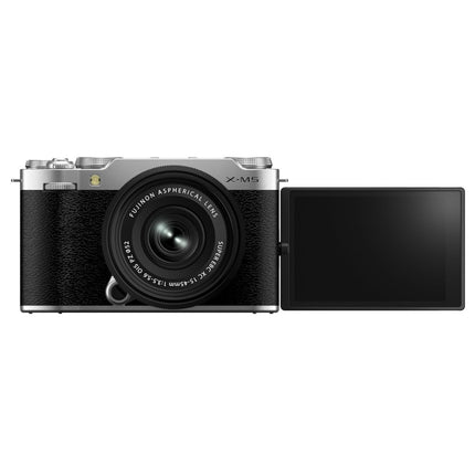 Fujifilm X-M5, silver/black, top-down flat lay with lens and lens cap beside camera