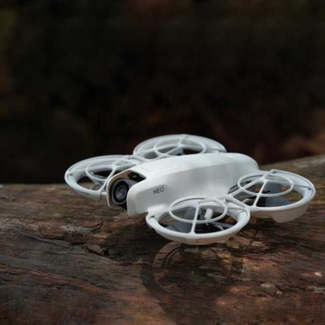 DJI Neo Drone, white/gray, angled top view in outdoor lifestyle setting