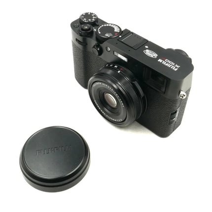 Fujifilm X100VI, black, front angled view with lens cap beside camera